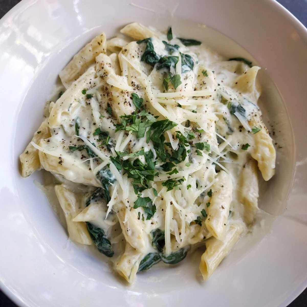 A close-up of The Magic Casserole showcasing the fresh, green spinach and bubbly cheese sauce.