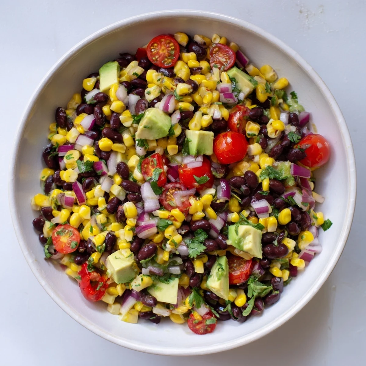 Bright bowl of Southwestern black bean and corn salad, garnished with cilantro and paired with chips.