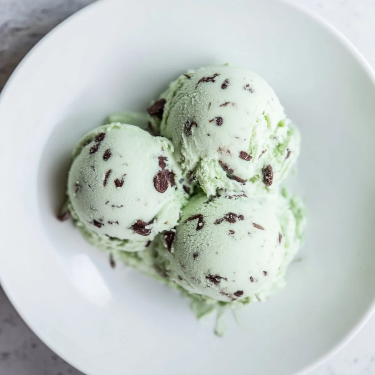 Creamy homemade Mint Chocolate Chip Ice Cream, swirled with chips, perfect for a summer treat.