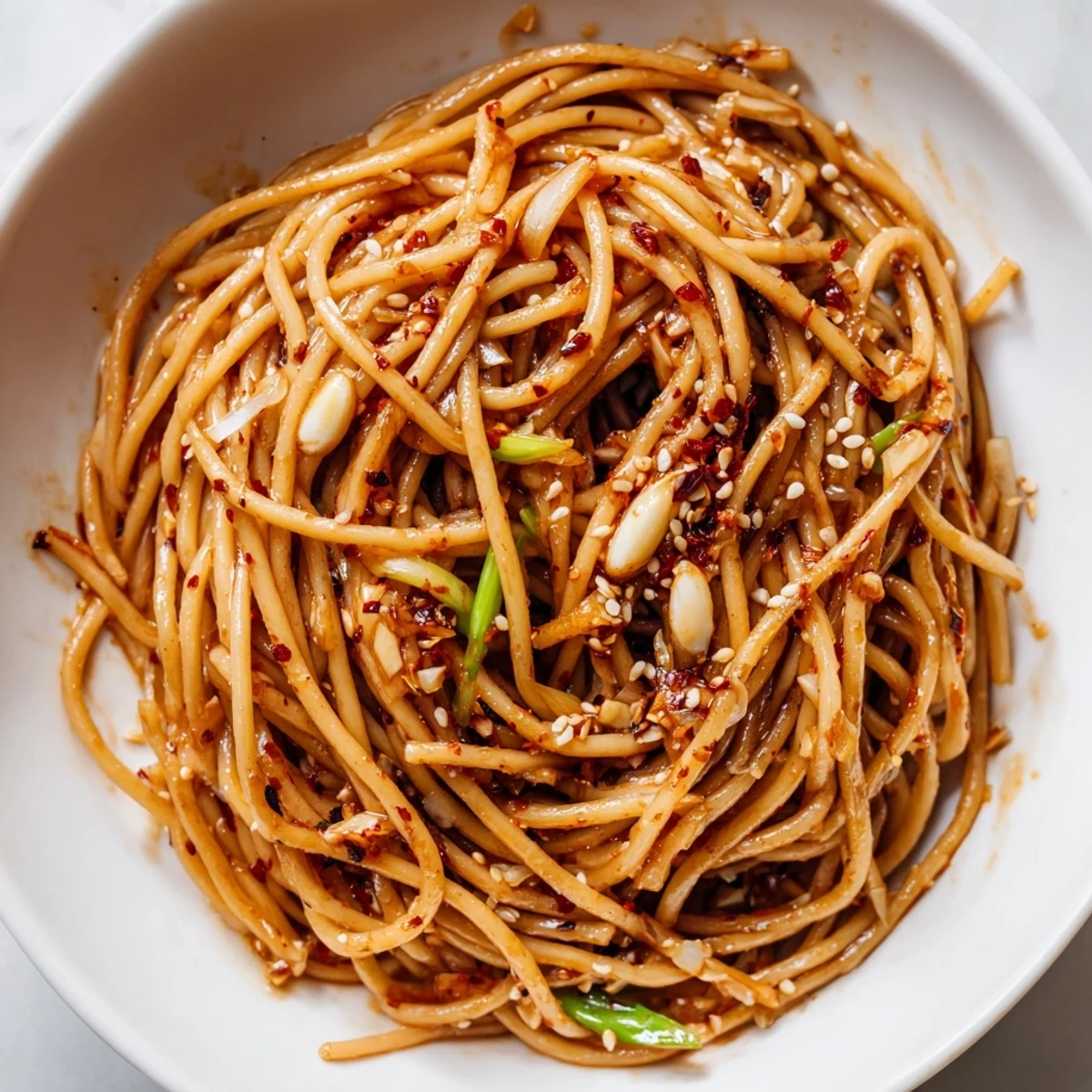 Golden, glistening Garlic Chili Oil Noodles tossed with vibrant green scallions, ready to enjoy.