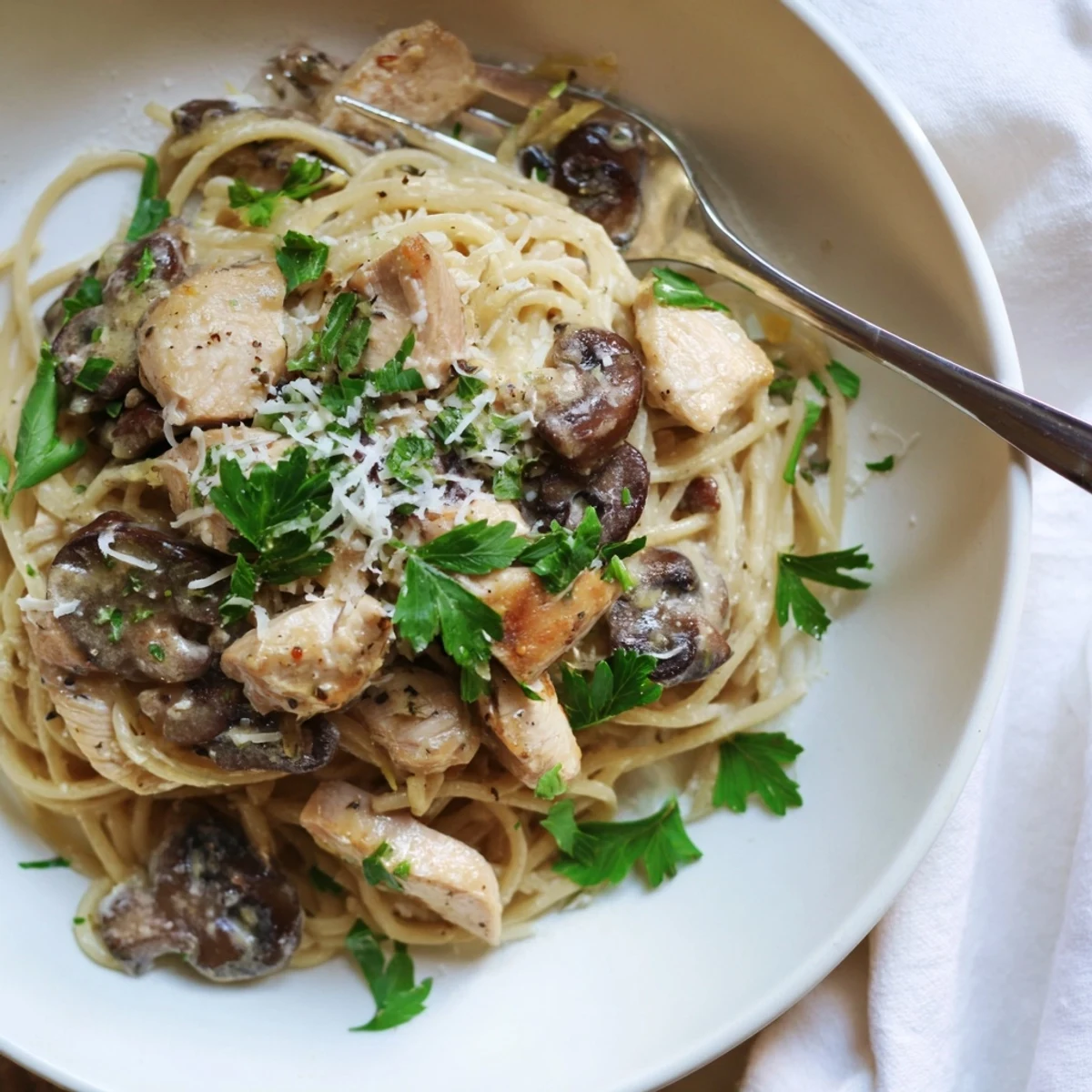 Creamy Mushroom Chicken Spaghettini plated on a white dish, featuring tender chicken strips and sautéed cremini mushrooms in a velvety, light cream sauce.