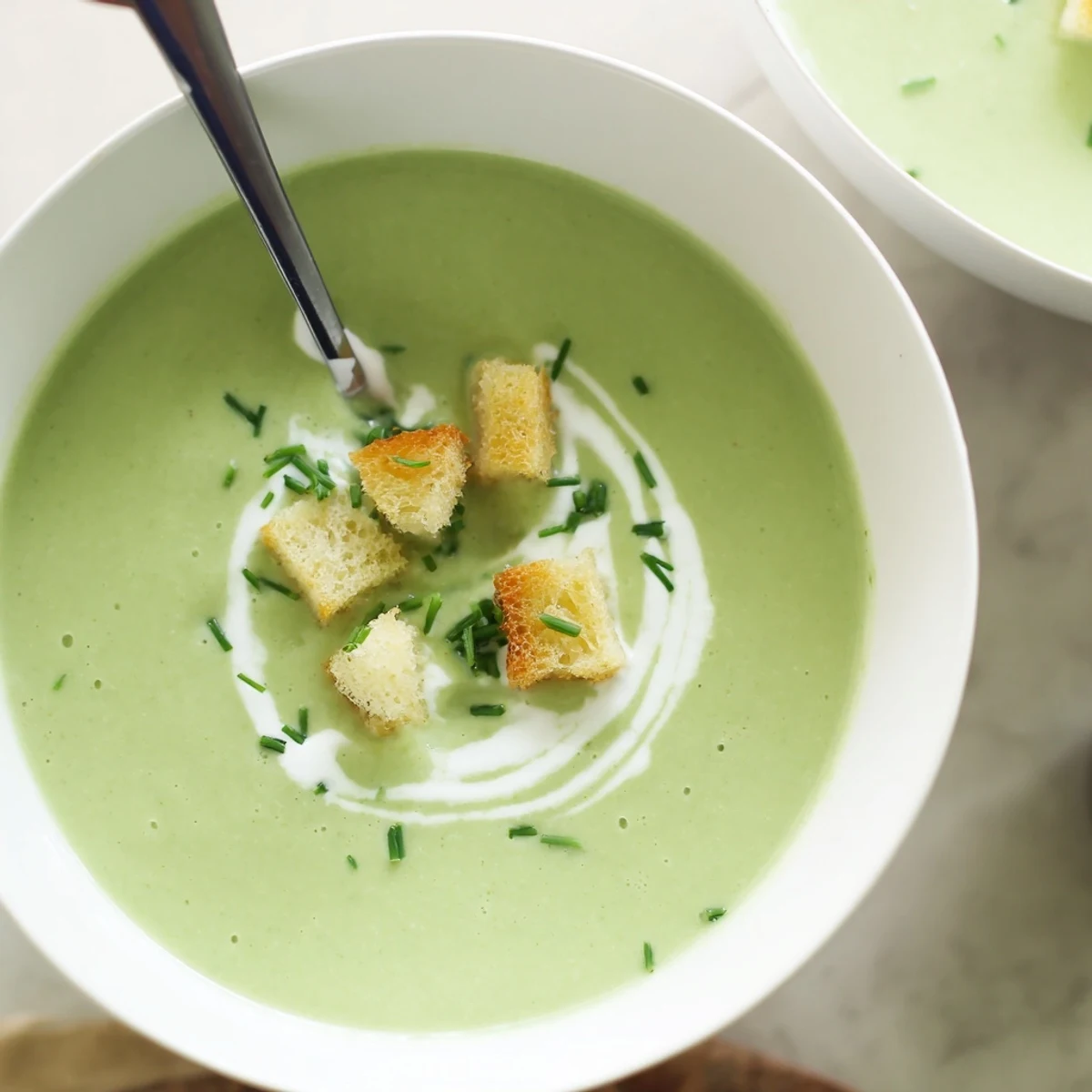 Creamy broccoli soup in a white bowl with a drizzle of olive oil and crunchy croutons, perfect for a cozy lunch.  
