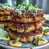 Freshly fried Asian-Style Tuna Cakes on a white plate, garnished with green onions and a small bowl of spicy mayo dip.