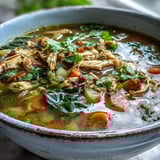 Golden Anti-Inflammatory Turmeric Chicken Soup garnished with fresh cilantro and lemon wedges on a cozy table.