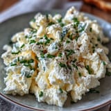 Protein-packed scrambled eggs blended with cottage cheese, garnished with fresh chives for a satisfying morning meal.  
