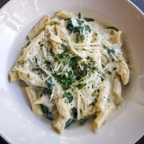 A close-up of The Magic Casserole showcasing the fresh, green spinach and bubbly cheese sauce.