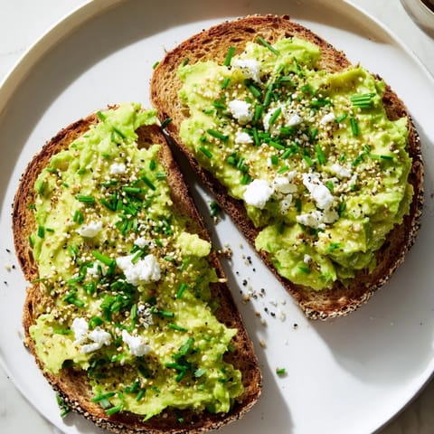 This vibrant photo shows avocado toast with everything, a vegetarian delight, ready to eat with a sprinkle.