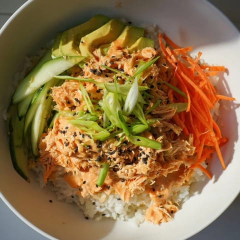 A close-up of a steaming Spicy Canned Salmon Rice Bowl, with vibrant toppings piled high.