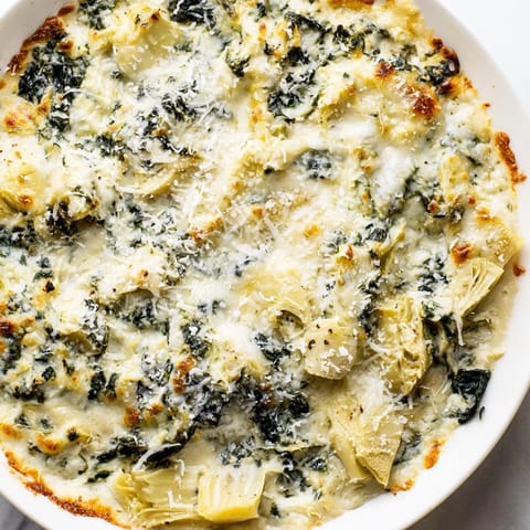 Warm spinach artichoke dip, a creamy mix of cheeses, spinach, and artichoke hearts, ready to bake.