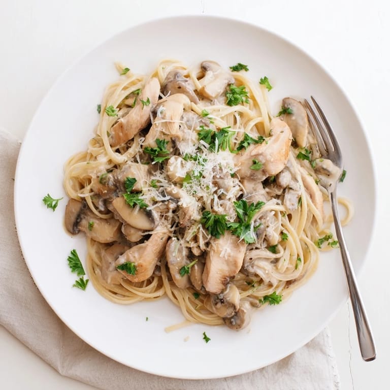 A close-up view of Creamy Mushroom Chicken Spaghettini showcasing the rich, silky mushroom sauce clinging to the skinny pasta and juicy chicken slices.