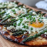 A crispy flatbread topped with tender asparagus, a perfectly baked egg, and parmesan cheese for a delicious brunch or dinner.